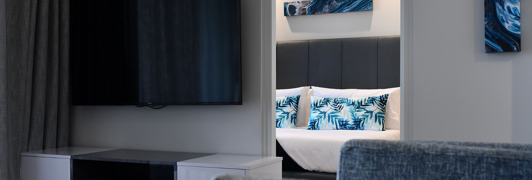 A modern hotel room with a bed, a TV, and a small desk.