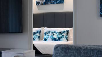 A modern hotel room with a bed, a TV, and a small desk.