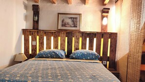 A bed with a floral-patterned bedspread, wooden headboard, and a framed picture on the wall. - An old oil press nestled between the sea and hiking trails (Santa-Reparata-Di-Balagna)