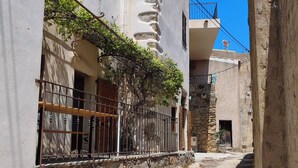 A narrow street with buildings, a stone wall, and a metal fence. - An old oil press nestled between the sea and hiking trails (Santa-Reparata-Di-Balagna)
