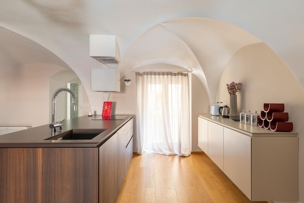 A modern kitchen with a central island, a built-in sink, and a window with sheer curtains.
