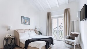 Un dormitorio con cama, mesita de noche, lámpara y una silla.