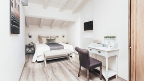 Un dormitorio con cama, mesita de noche, silla, escritorio y televisor.