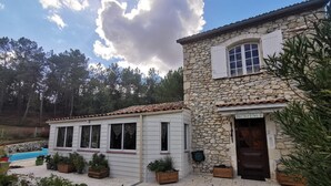 Un edificio de piedra con tejado de tejas y terraza de madera. Hay un cartel en la puerta que dice 