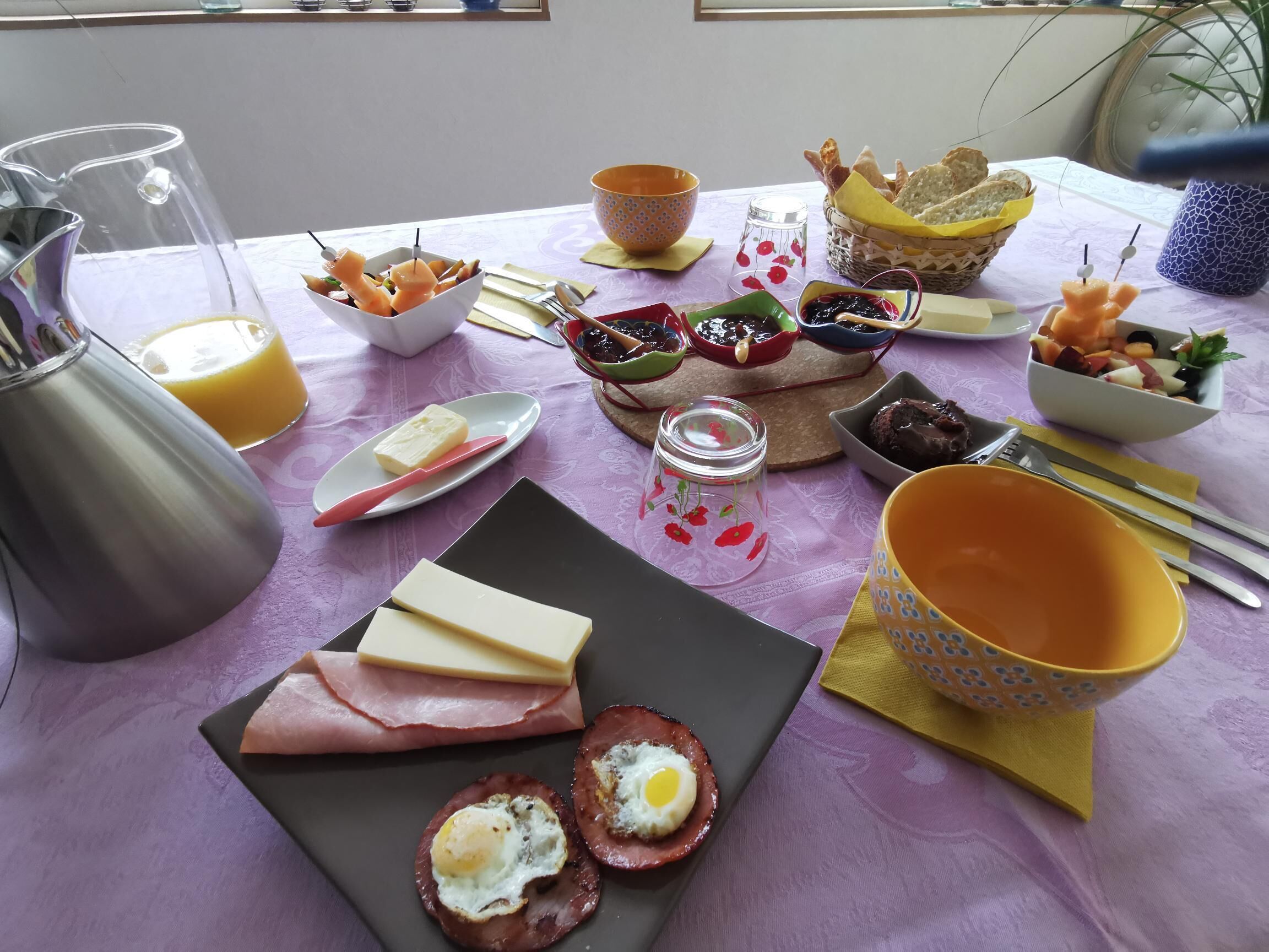 Una mesa de desayuno con diversos alimentos, entre ellos huevos, queso y pan.