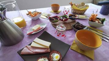 Una mesa de desayuno con diversos alimentos, entre ellos huevos, queso y pan.