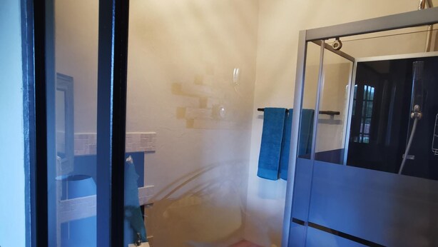Een compacte badkamer met een houten vloer, een klein wastafeltje en een toilet.