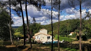 Una casa de piedra con techo de tejas, rodeada por un patio cercado y una piscina.