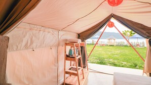 Una carpa con un estante de madera, un farol rojo y vistas a un lago y montañas.