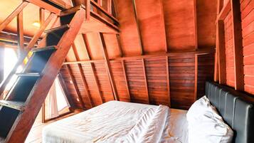 A wooden room with a bed, a ladder, and a sloped ceiling.