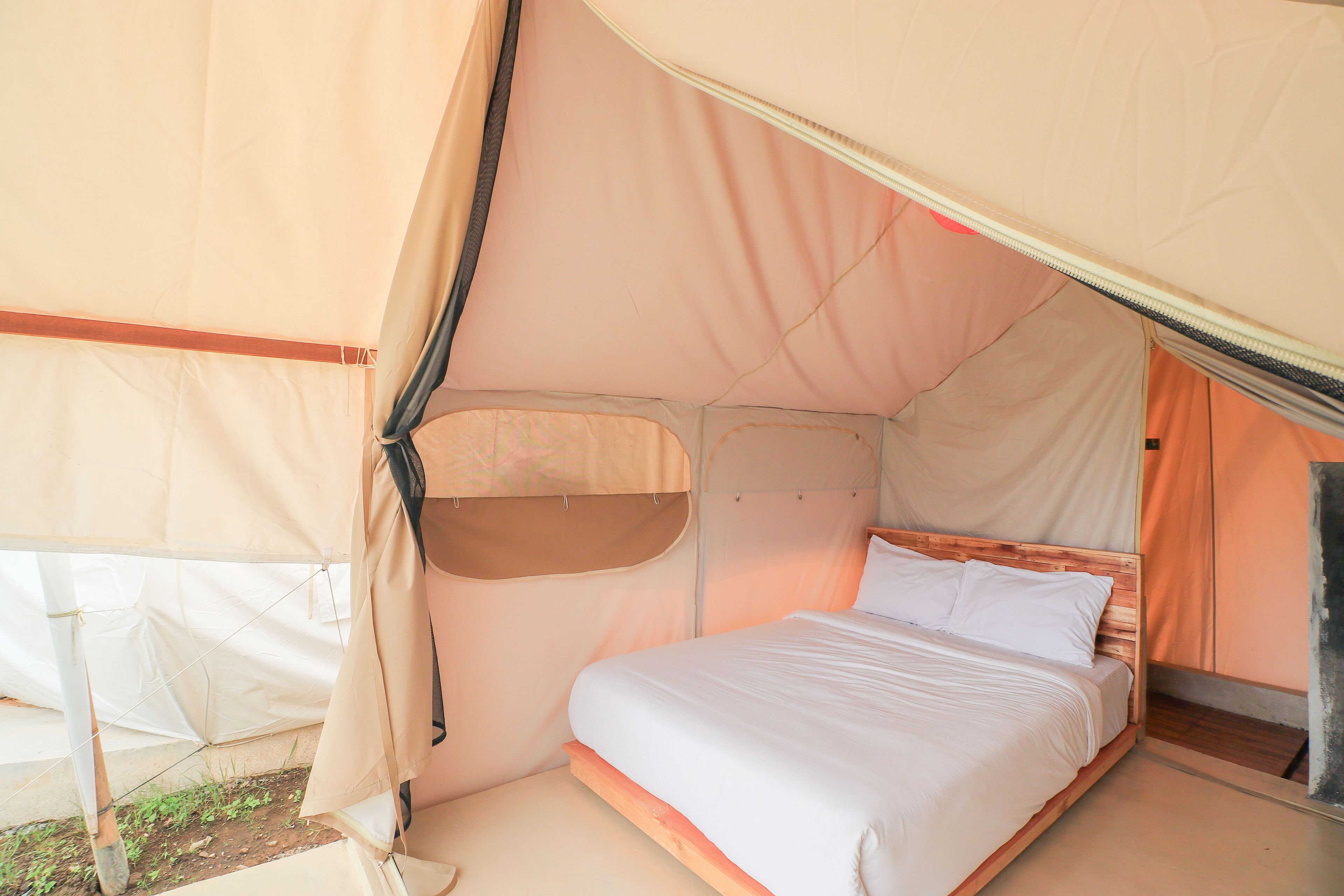 A single bed in a tent with a wooden headboard and a canopy.