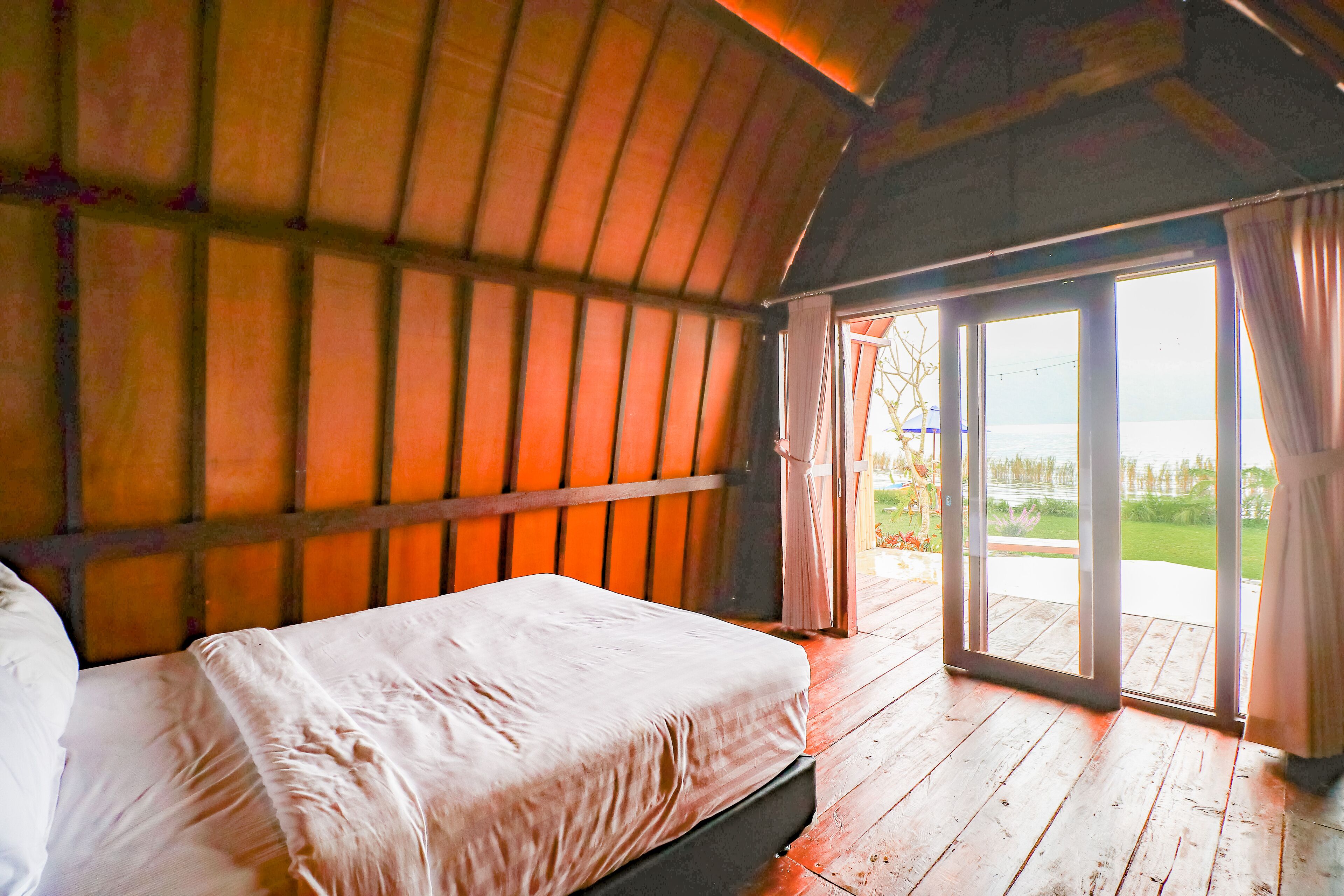 Ein Zimmer mit einem Bett, Holzwänden und Blick durch eine Glastür.