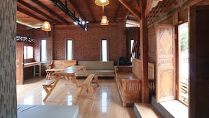 Un interior rústico con vigas de madera a la vista, pared de ladrillo y un rincón con banco de madera.