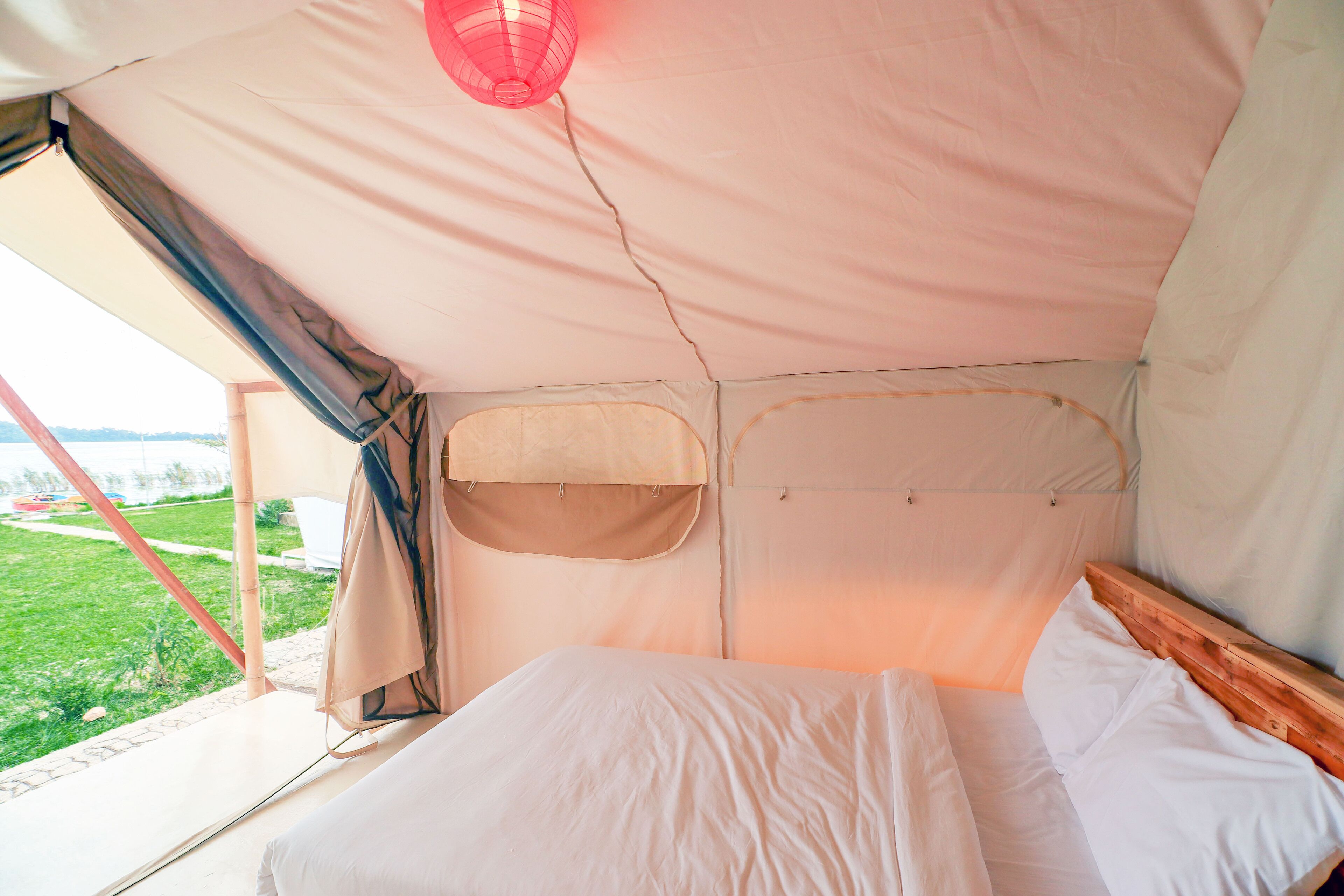 Une pièce aménagée avec une tente, un lit, une fenêtre et donnant sur un espace verdoyant.