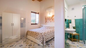 A bedroom with a bed, wardrobe, and a bathroom with a sink and shower.