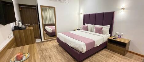 Et moderne hotelværelse med en stor seng, sengeborde, et spejl, et klædeskab og en aircondition.