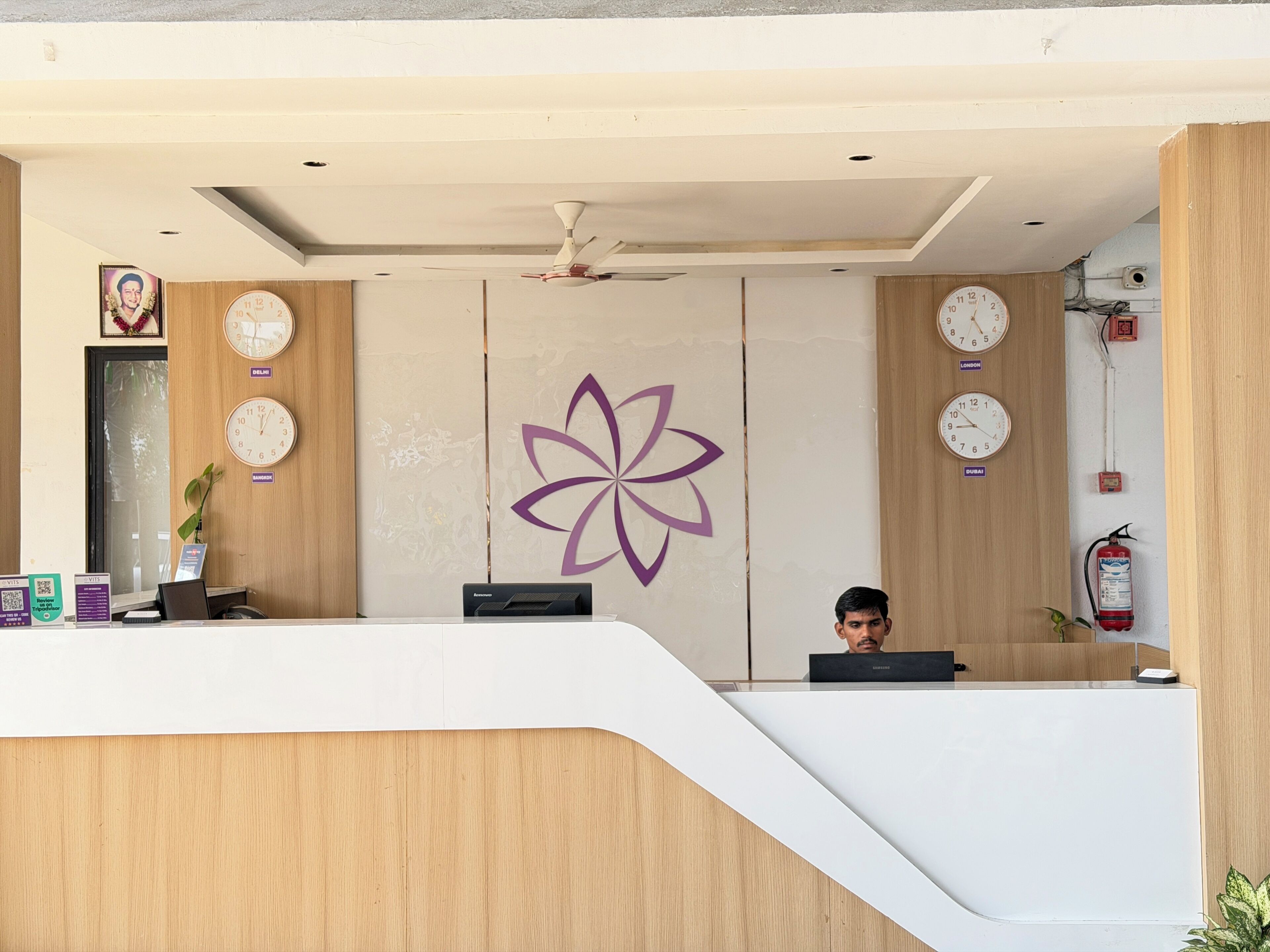 A reception desk with clocks, a logo, and a fire extinguisher.