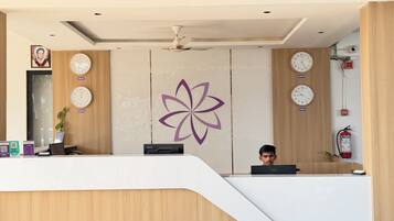 A reception desk with clocks, a logo, and a fire extinguisher.