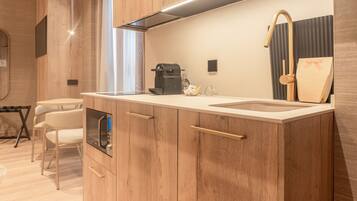 Una cocina moderna con armarios de madera, un microondas integrado, una cafetera y un fregadero.