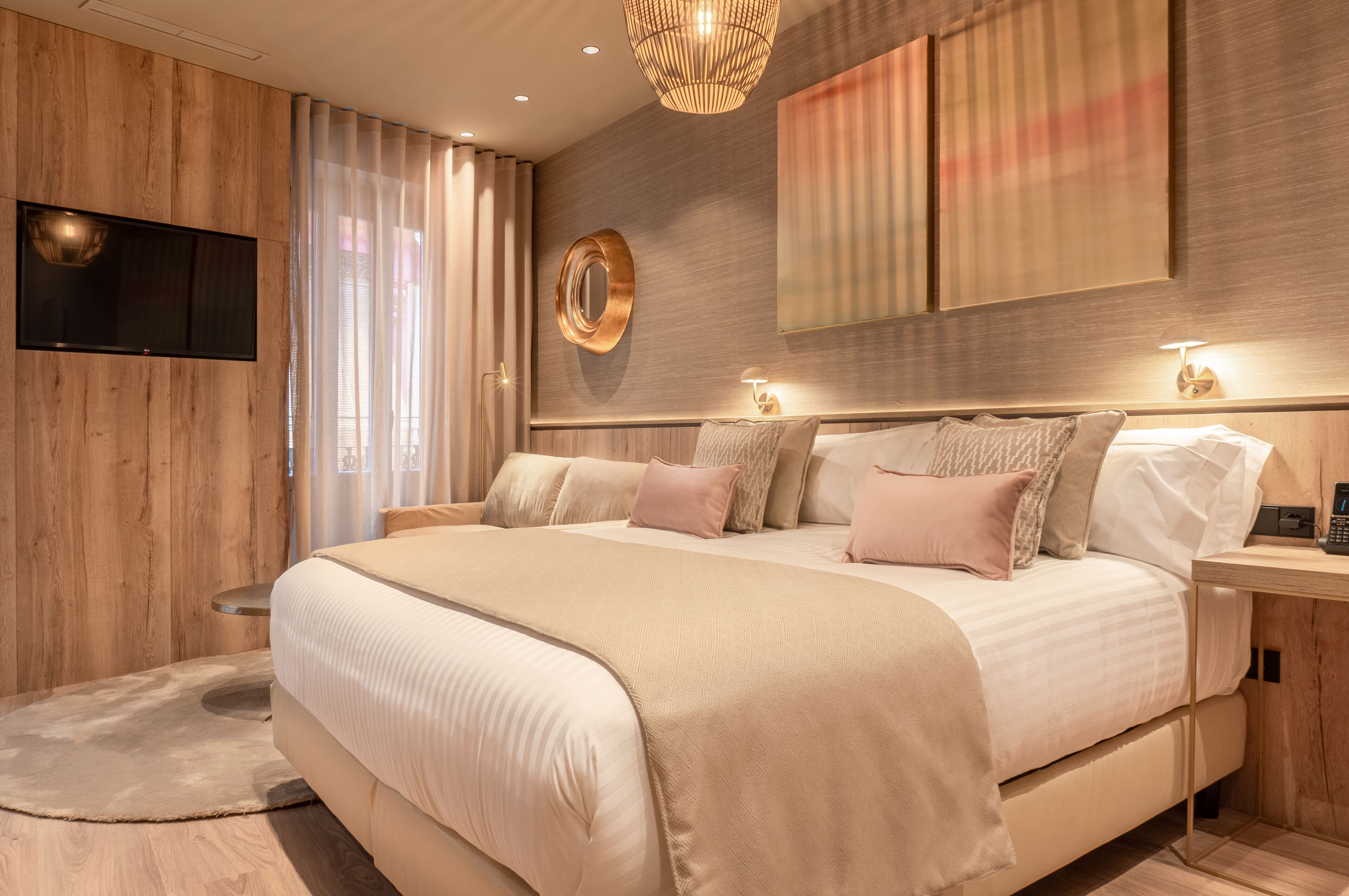 A modern bedroom with a large bed, a mounted TV, and a wooden accent wall.