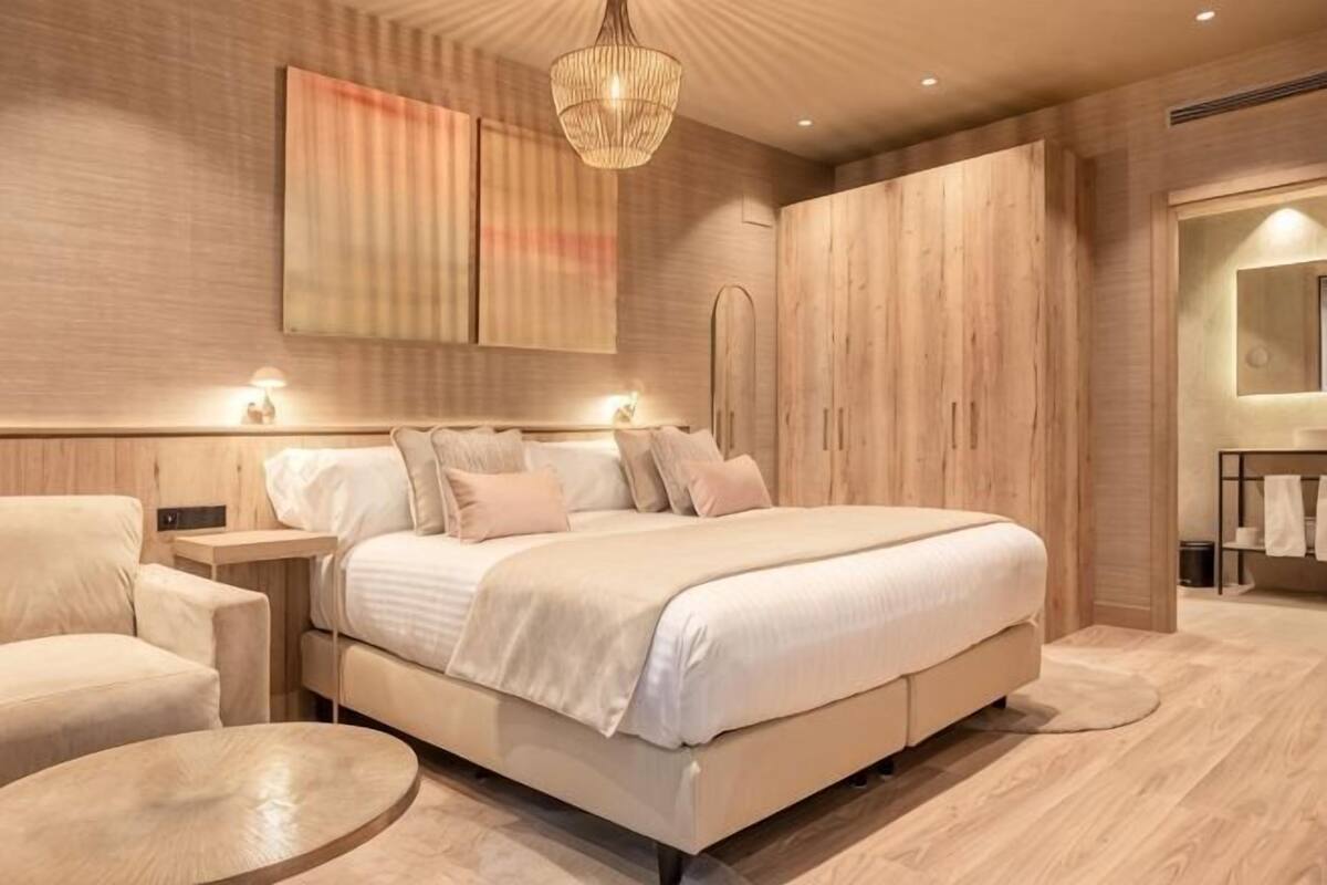 A modern bedroom with a large bed, bedside tables, a chair, and a round table.
