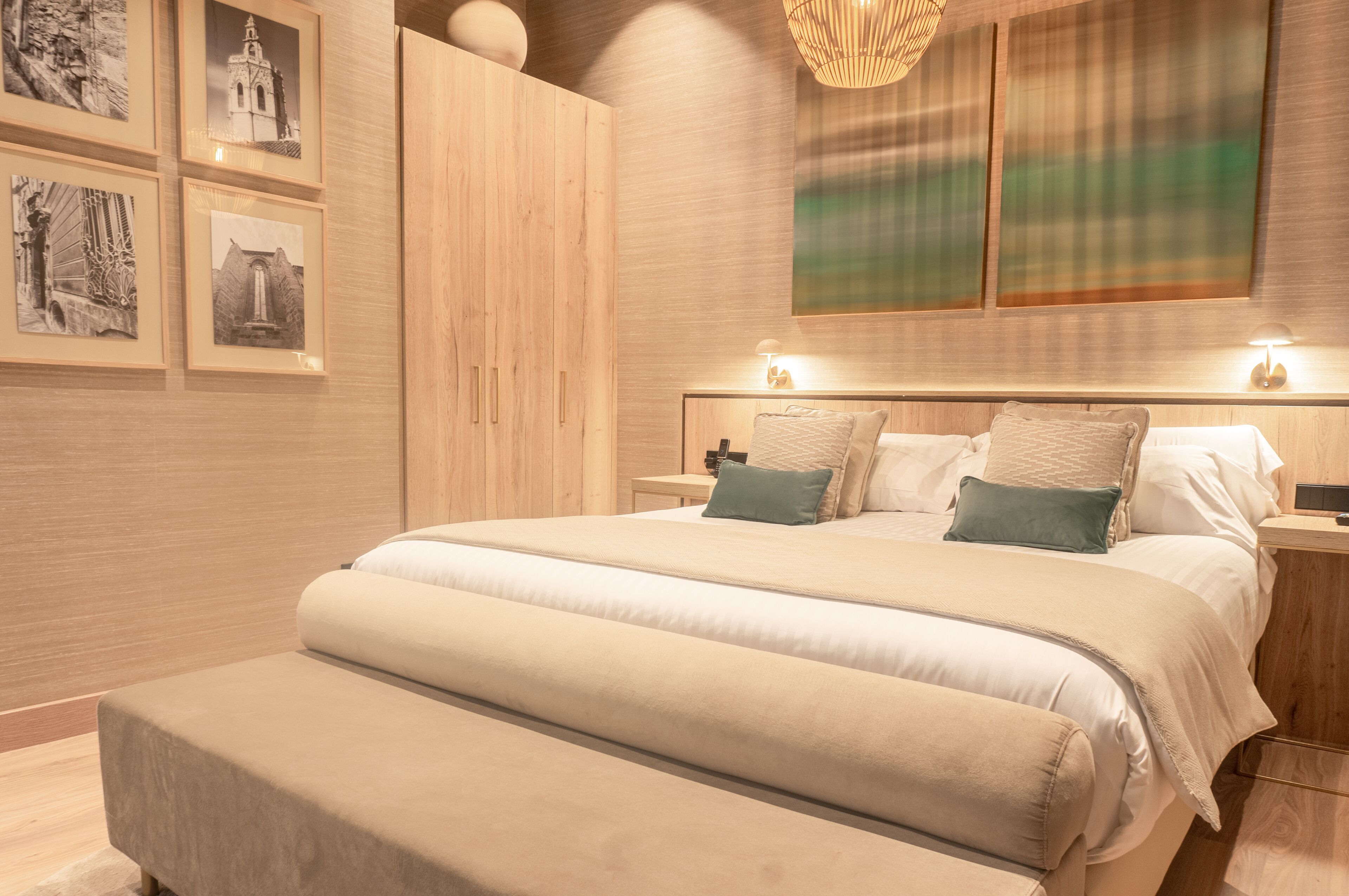 A modern bedroom with a large bed, wooden wardrobe, and framed pictures on the wall.