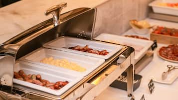 Un bufé con diversas opciones de comida, incluyendo salchichas, huevos revueltos y otros platos.