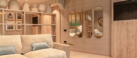 Una sala de estar moderna con un sofá color beige, una mesa de centro redonda y una pared de madera con estantes empotrados que exhiben objetos decorativos.
