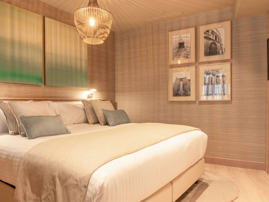 Ein Schlafzimmer mit einem großen Bett, einem Holzkopfende, einer hängenden Lampenleuchte und gerahmten Bildern an der Wand.