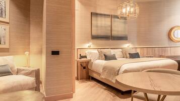 Quarto moderno com cama grande, mesas de cabeceira, mesa redonda e luminária pendente.