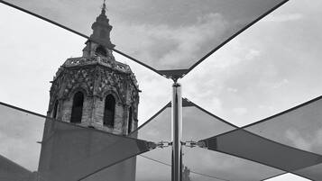 Un edificio histórico con un campanario y una estructura moderna con estructura metálica en primer plano.