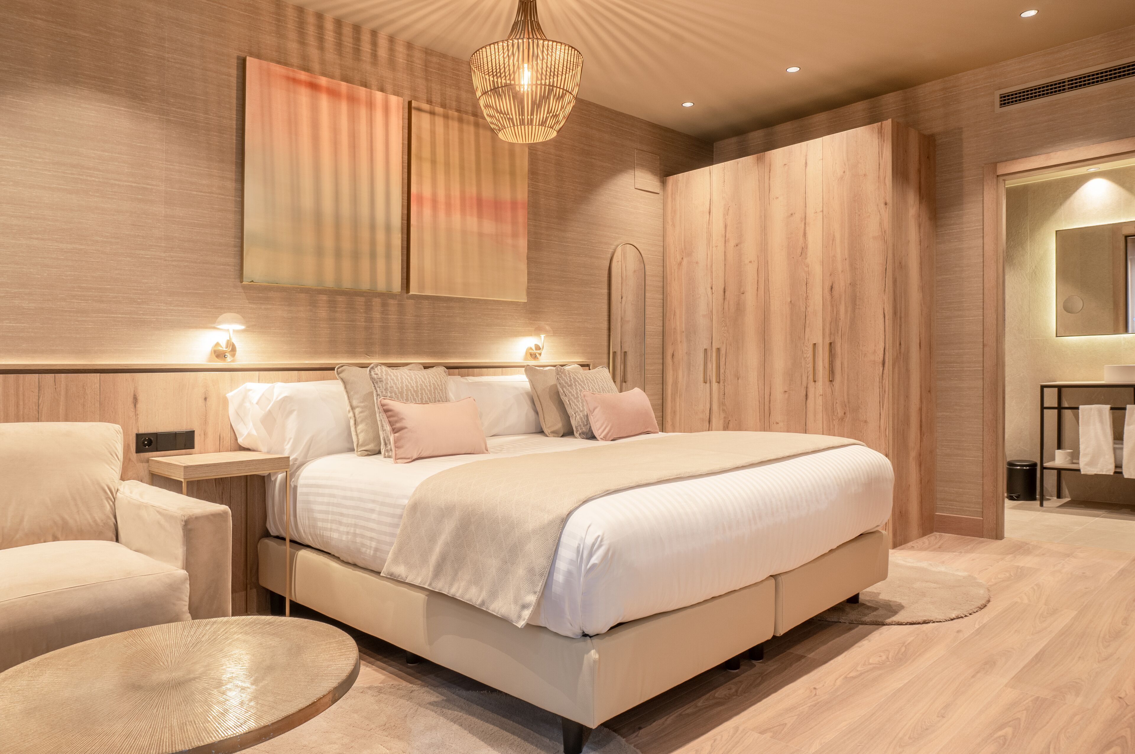 Een moderne slaapkamer met een groot bed, nachtkastjes, een ronde salontafel en een kledingkast.