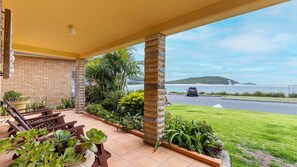 Enjoy a serene view of the water and distant island from this outdoor space, surrounded by lush greenery and a comfortable bench.