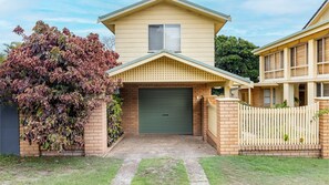 Stunning two-story home with a central entrance, brick pillars, and a charming porch.