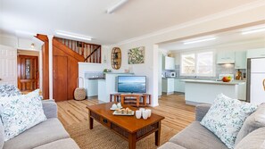 Relax in this stylish living room with a comfortable sofa, coffee table, and TV, plus a staircase leading to more space.