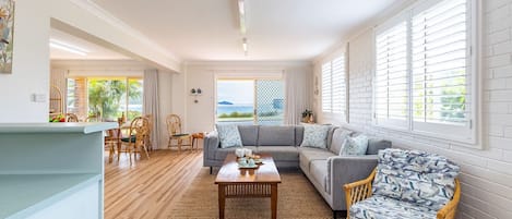 Ein geräumiges Wohnzimmer mit einer großen Couch, einem Couchtisch und einem Essbereich mit Stühlen und Tisch.