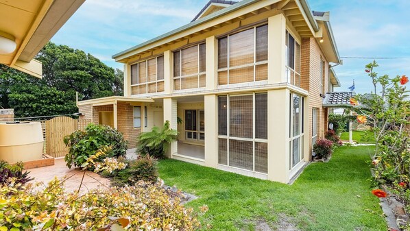 A two-story house with a large front porch, a covered patio, and a well-maintained garden.