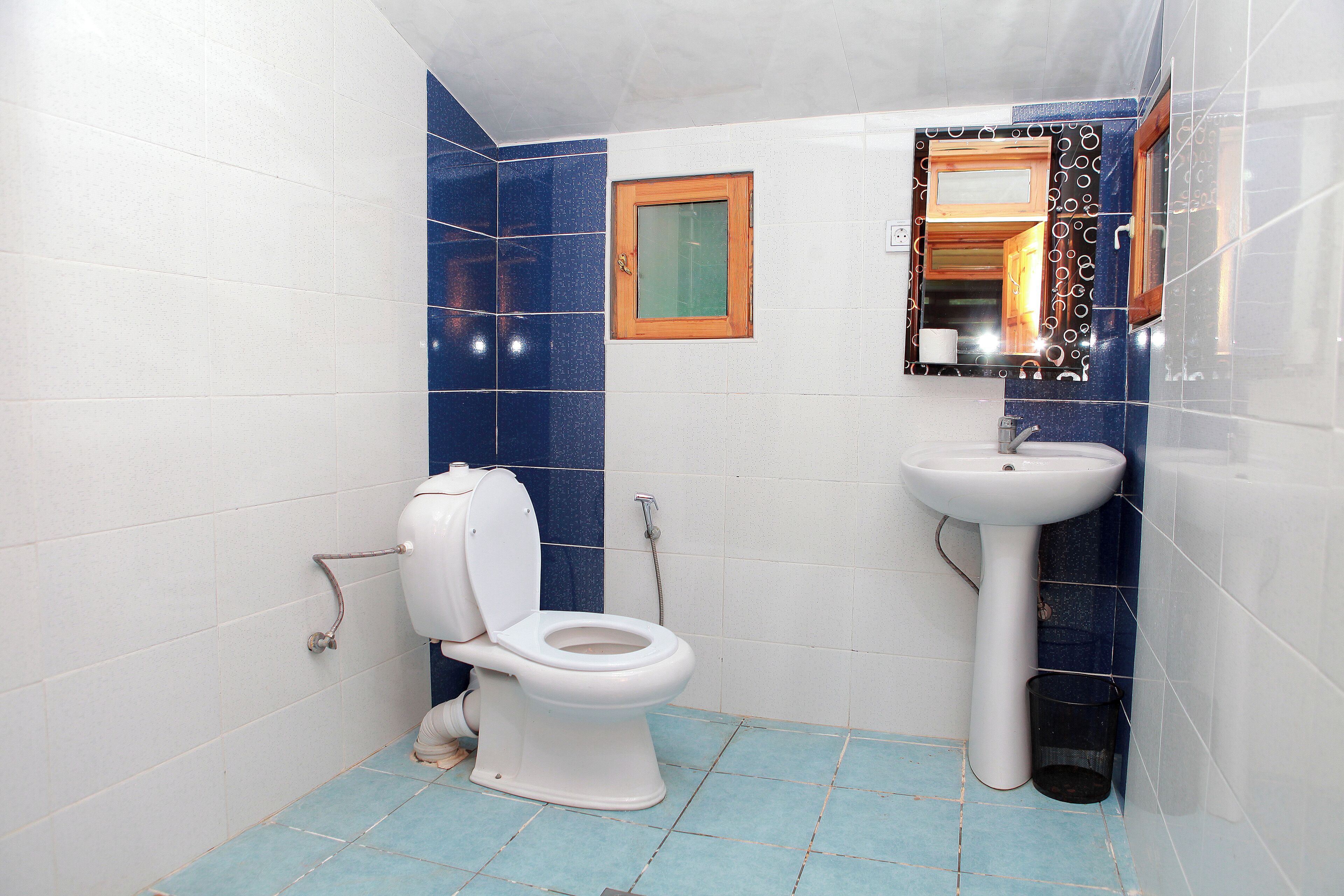 A bathroom with a toilet, sink, and blue-tiled walls.
