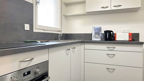 A modern kitchen with white cabinets, a built-in oven, a coffee maker, and a toaster.