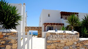 A stone wall with a sign reading "AIAOZE HOTEL" and a white gate. - Aeolos Hotel (Naxos)