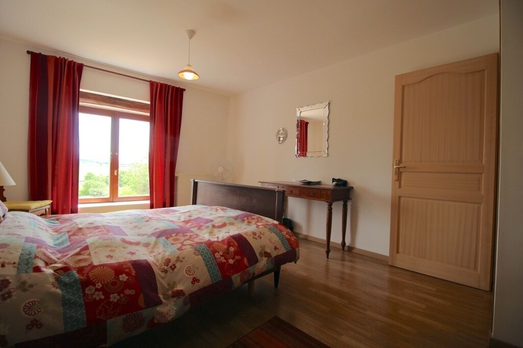 Un dormitorio con cama, escritorio, espejo y puerta.