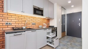 A modern kitchen with white cabinets, a brick backsplash, and a black microwave. - Stylish Studio | Terrace, Air Conditioning, Center (Kraków)
