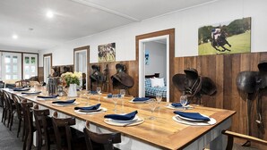 A long wooden dining table set with blue napkins, wine glasses, and plates, flanked by horse tack on the walls. - Fentons Run, High Range, Southern Highlands (High Range)