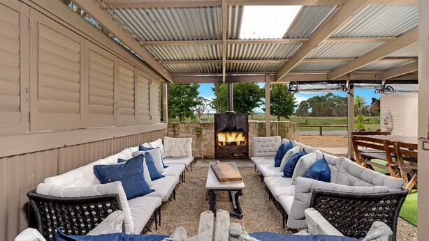 An outdoor seating area with a fire pit, white cushioned sofas, and a pergola structure. - Fentons Run, High Range, Southern Highlands (High Range)