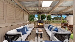 An outdoor seating area with a fire pit, white cushioned sofas, and a pergola structure. - Fentons Run, High Range, Southern Highlands (High Range)