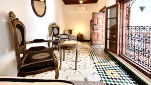 A room with a checkered floor, wooden furniture, a mirror, and a view through a window with decorative ironwork. - Dar Malika · Traditional Fez house with spectacular view (Fes)