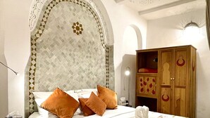 A hotel room with a bed, a wooden wardrobe, and a decorative wall. - Dar Malika · Traditional Fez house with spectacular view (Fes)