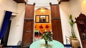 A traditional interior with a central round table, wooden doors, and a hanging chandelier. - Dar Malika · Traditional Fez house with spectacular view (Fes)