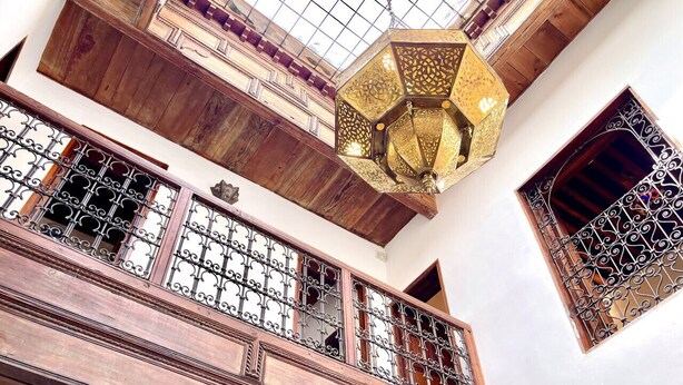 A wooden balcony with intricate metal railings and a decorative hanging light fixture. - Dar Malika · Traditional Fez house with spectacular view (Fes)