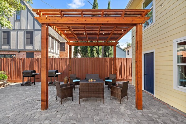 A covered patio area with wicker furniture and a grill.